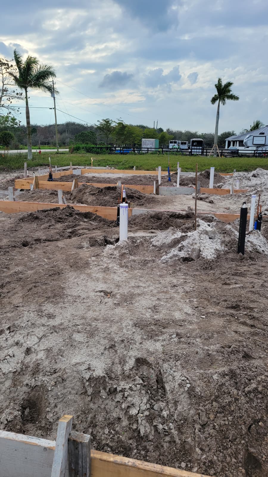 Construction site with marked foundations, wooden forms, and exposed soil, indicating preparation for new building development.